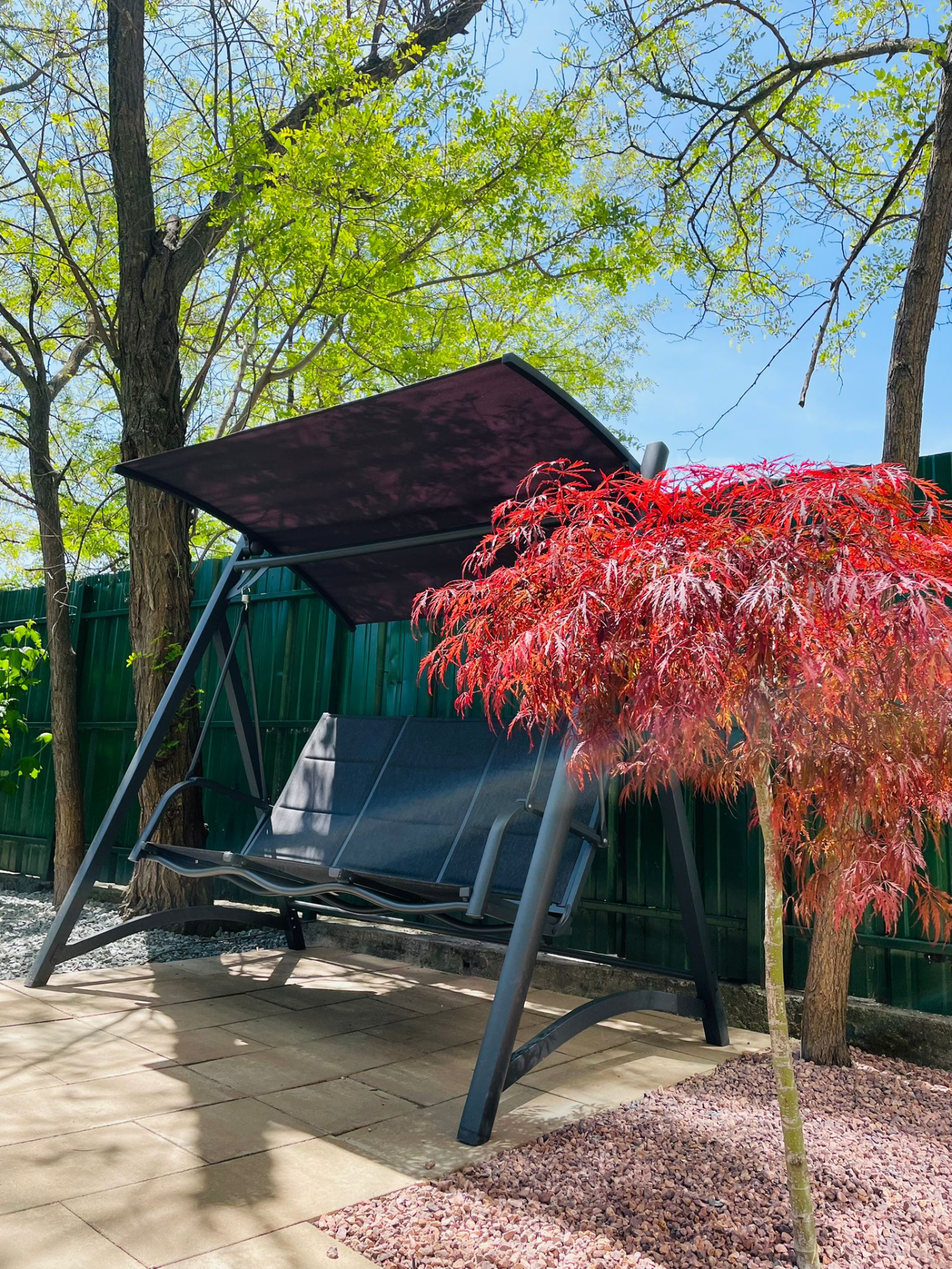 Leagan dublu cu pergola amplasata intr-o gradina cu artar rosu si pavaj din piatra pentru seniori